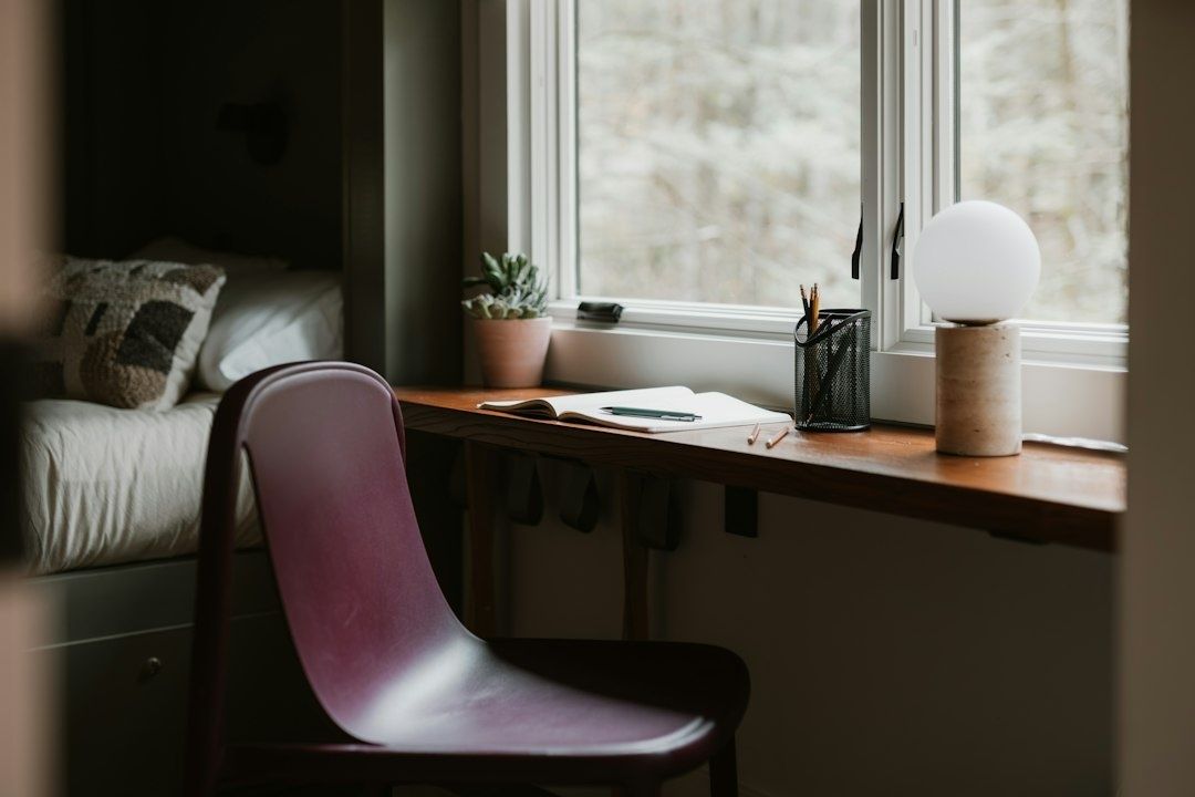 Rolig arbeidsplass med notatbok ved vinduet og en tom stol